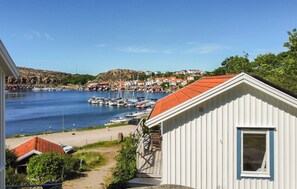 A coastal view with a marina, boats, and a small white building with a red roof. - Beach front home in Kungshamn Hovenäset with sauna (Kungshamn Hovenäset)