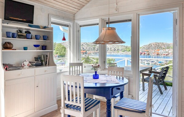 A sunlit room with a dining table, chairs, a TV, and a view of a harbor. - Beach front home in Kungshamn Hovenäset with sauna (Kungshamn Hovenäset)