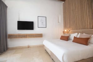 A bedroom with a bed, a flat-screen TV mounted on the wall, and a framed artwork. - Luxury Room in Casa Escallon (Cartagena)
