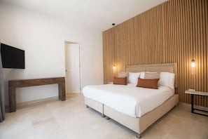 A bedroom with a bed, bedside table, and a wall-mounted TV. - Luxury Room in Casa Escallon (Cartagena)
