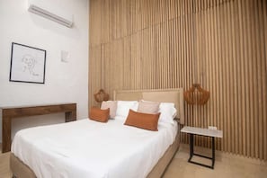 A bedroom with a bed, bedside tables, a hanging light fixture, and a wall-mounted air conditioner. - Luxury Room in Casa Escallon (Cartagena)