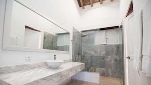 Ein modernes Badezimmer mit Marmorwaschtisch, einem großen Spiegel und einer Duschkabine.