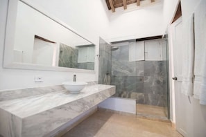 A modern bathroom with a marble vanity, a large mirror, and a glass-enclosed shower area. - Luxury Room in Casa Escallon (Cartagena)
