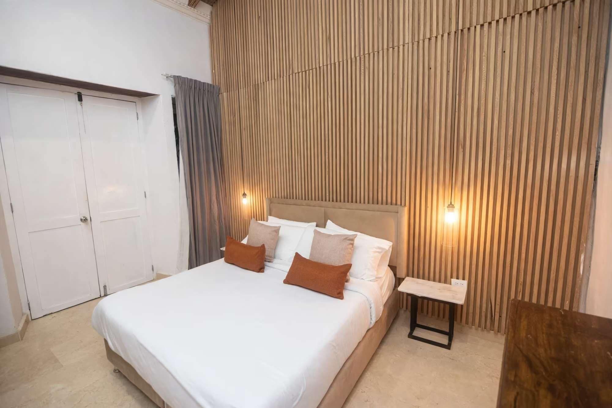 Um quarto com cama, mesa de cabeceira e guarda-roupa.