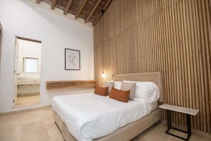 A bedroom with a bed, a bedside table, a wooden slat wall, and a framed picture on the wall. - Luxury Room in Casa Escallon (Cartagena)