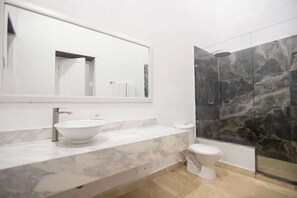 A bathroom with a marble sink, a toilet, and a shower with dark tiles. - Luxury Room in Casa Escallon (Cartagena)