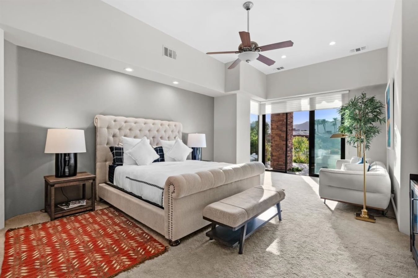 Bedroom #1 (primary): King bed with ensuite bath, nightstands, table lamps, smart tv, dresser, designated work space, accent chair, walk-in closet, luggage racks, ceiling fan, access to backyard with sliding glass wall