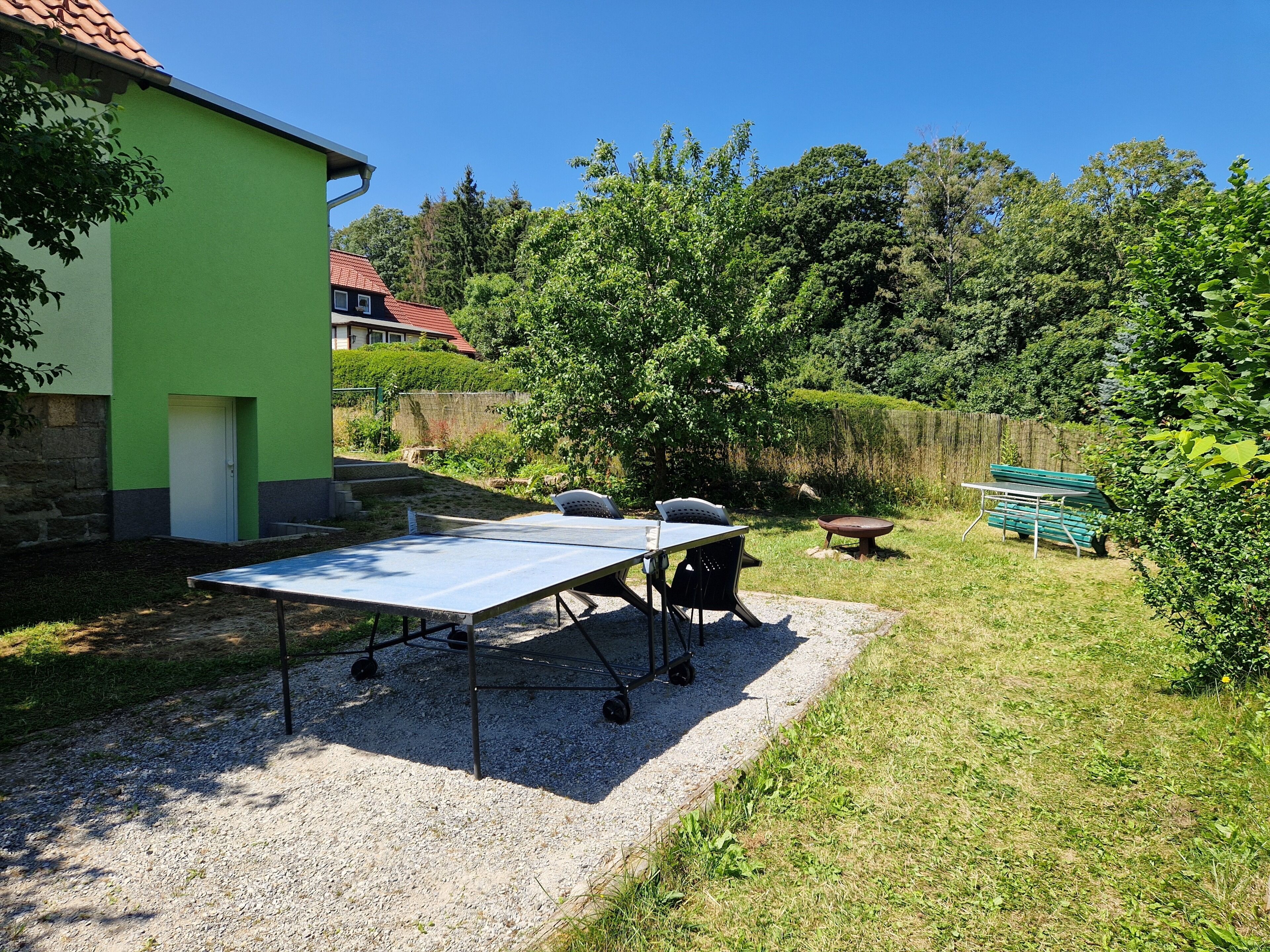 Ein Innenhof mit einem Tischtennis-Tisch, Sitzgelegenheiten im Freien und einem grünen Gebäude.