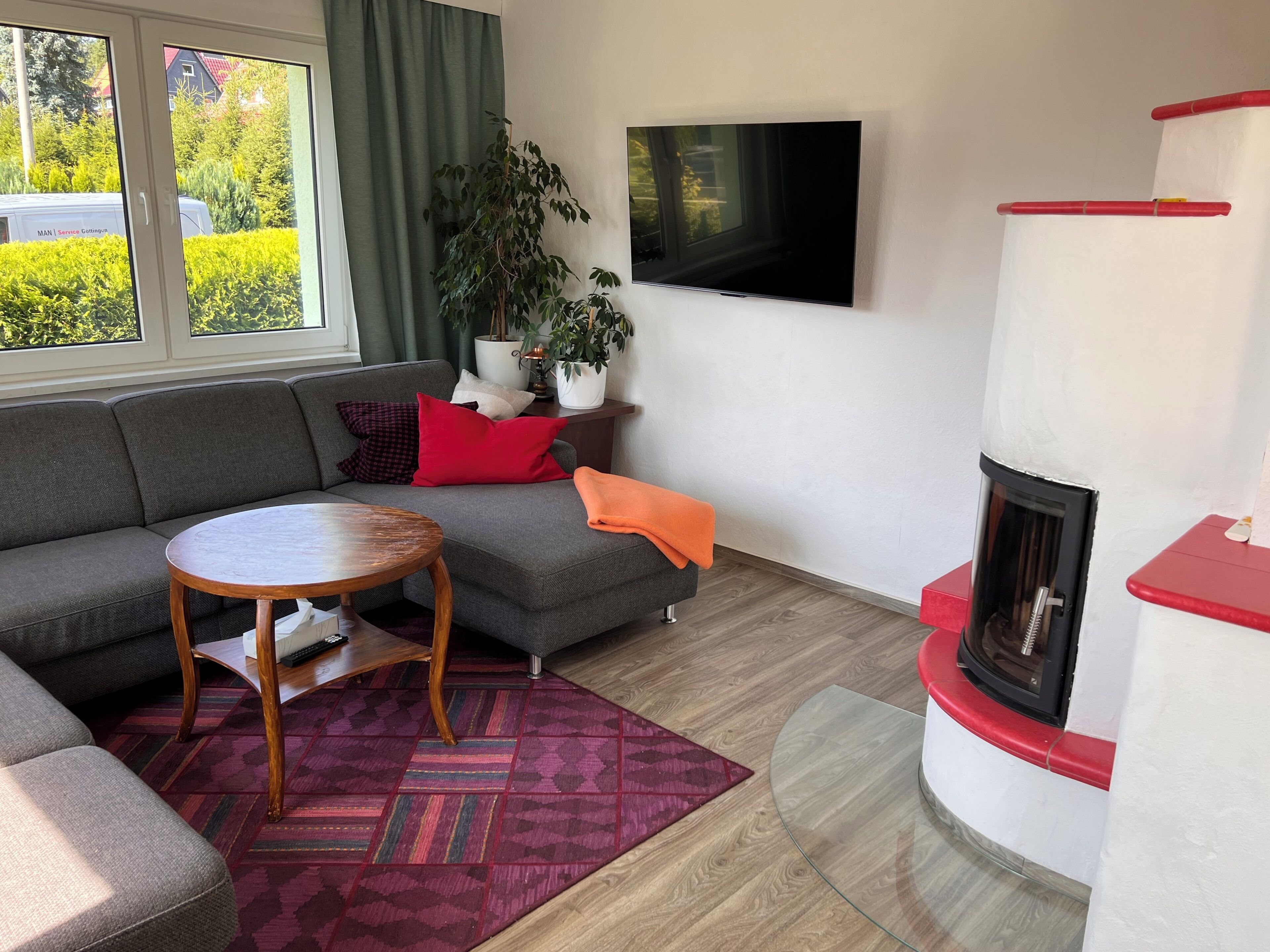 Ein Wohnzimmer mit einer Couch, einem kleinen Tisch, einem Kamin und einem Fernseher an der Wand.