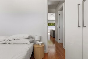 Ein Schlafzimmer mit Bett, Nachttisch, Lampe und Blick auf einen Balkon.