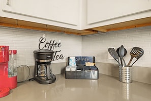 A kitchen with a coffee maker, a coffee station, and kitchen utensils. - New Stylish Indy Apt- Perfect for Groups - 3BR (Indianapolis)