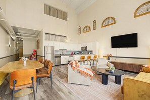 A spacious living area with a dining table, sofas, and a kitchen in the background. - New Stylish Indy Apt- Perfect for Groups - 3BR (Indianapolis)