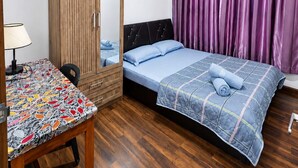 A bedroom with a bed, a wardrobe, a table, and a lamp.
