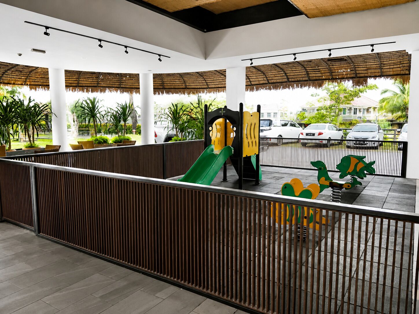 An outdoor play area with a slide, climbing structure, and decorative dinosaur figures.