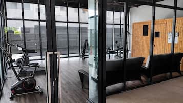 Een fitnessruimte met trainingsapparatuur, een bank en een muur met een plaquette.