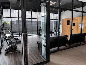 Une salle de sport équipée de matériel d’exercice, d’un banc et d’un mur portant une plaque commémorative.