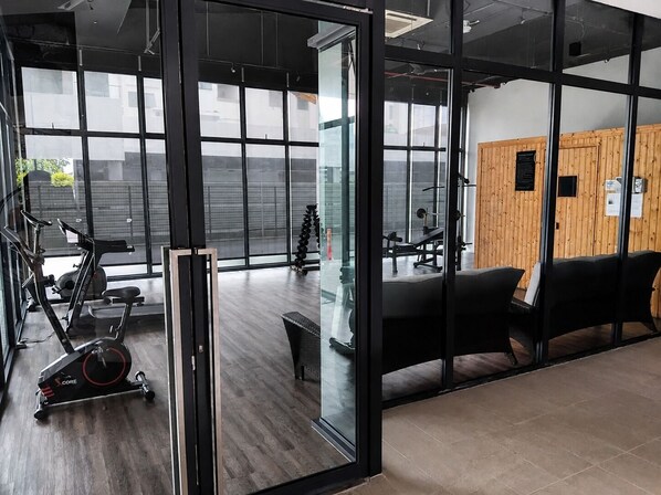 A gym with exercise equipment, a bench, and a wall with a plaque.