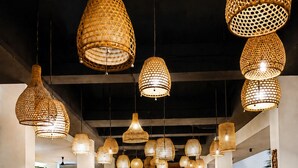 A spacious indoor area with multiple seating arrangements and hanging wicker lamps.