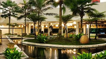 A hotel lobby with a central water feature, surrounded by palm trees and plants.