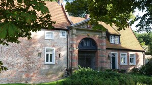En murbygning med et tagdækket tag, en midterlig buegang og et lille vindue på øverste etage.