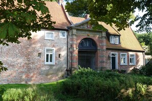 A brick building with a tiled roof, a central arched entrance, and a small window on the upper floor. - Vrbo Property (Hage)
