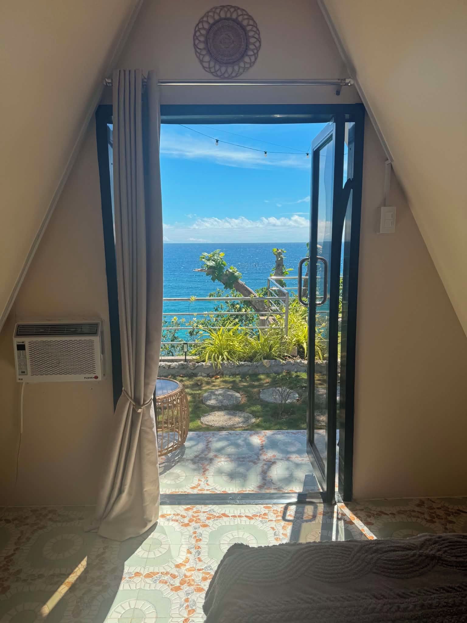 Ein Zimmer mit Meerblick, ein Fenster mit Vorhängen, ein Heizkörper und ein fußbodenmuster.