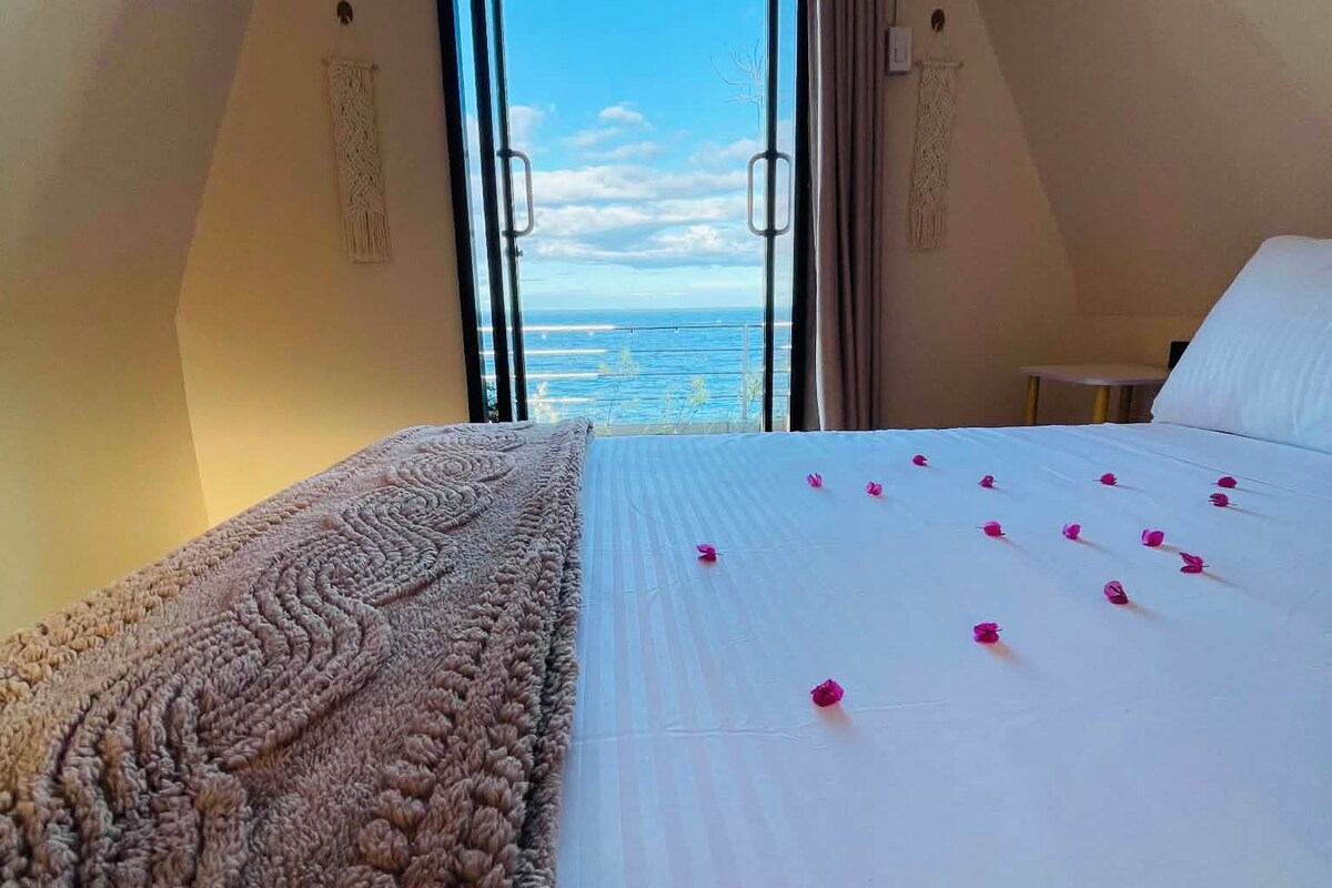 A bedroom with a bed, a view of the sea, and a window.