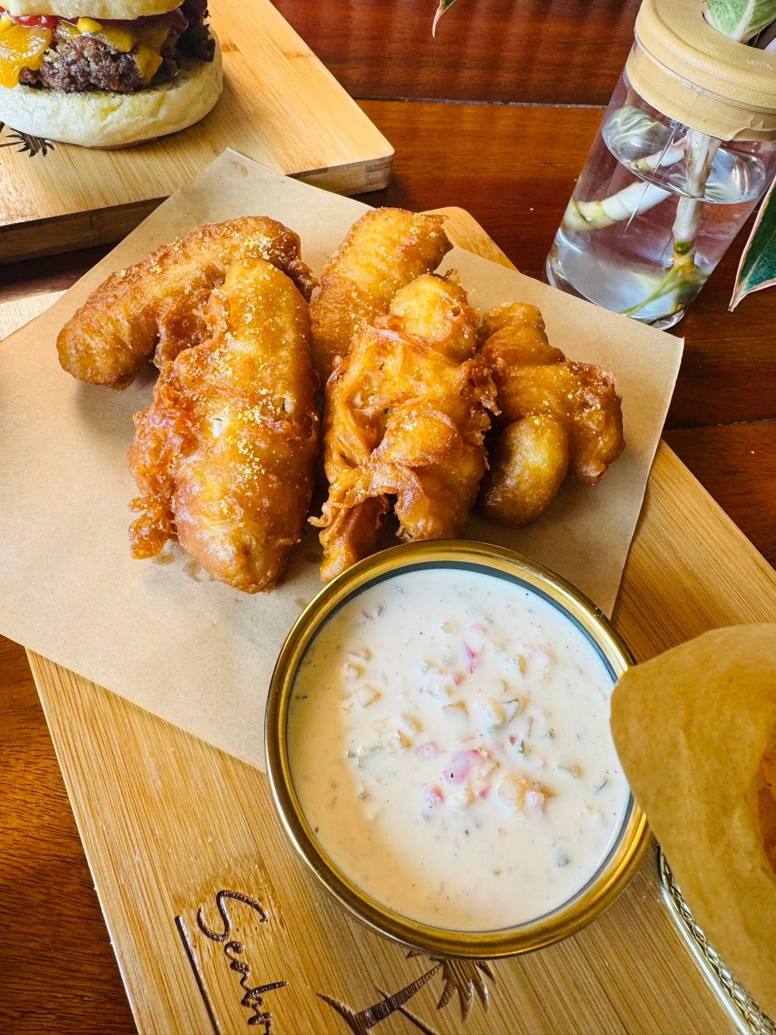 A wooden table with a plate of fried chicken wings and a bowl of dipping sauce.
