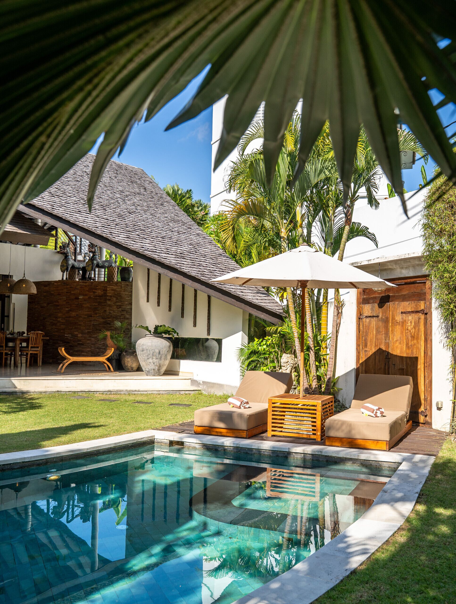 A poolside area with a lounge chair, a wooden deck, and a large umbrella.