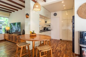 A modern kitchen with a round wooden table, two wicker chairs, a hanging light fixture, and a refrigerator. - Private Pool | Garden Lounge | Dedicated Workspace (Canggu)