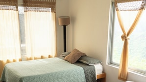 Een kamer met twee bedden, een nachtkastje, een lamp en een raam met gordijnen.