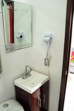 A bathroom with a white sink, a mirror, and two hair dryers mounted on the wall. - Vrbo Property (Tonalá)