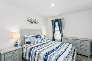 Un dormitorio con una cama, dos mesitas de noche, una lámpara de pared, una ventana con cortinas y una luz en el techo.