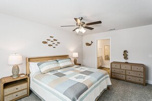 A bedroom with a bed, nightstands, a dresser, a ceiling fan, and wall decorations. - Gulf Breeze 3BR Townhome | Pool & Playground | Near Zoo, Navarre Beach & Pensacola (Gulf Breeze)