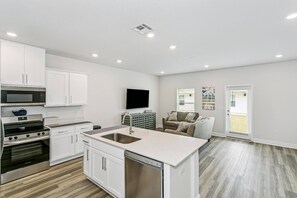 Una cocina moderna con armarios blancos, electrodomésticos de acero inoxidable y una isla central con pileta.