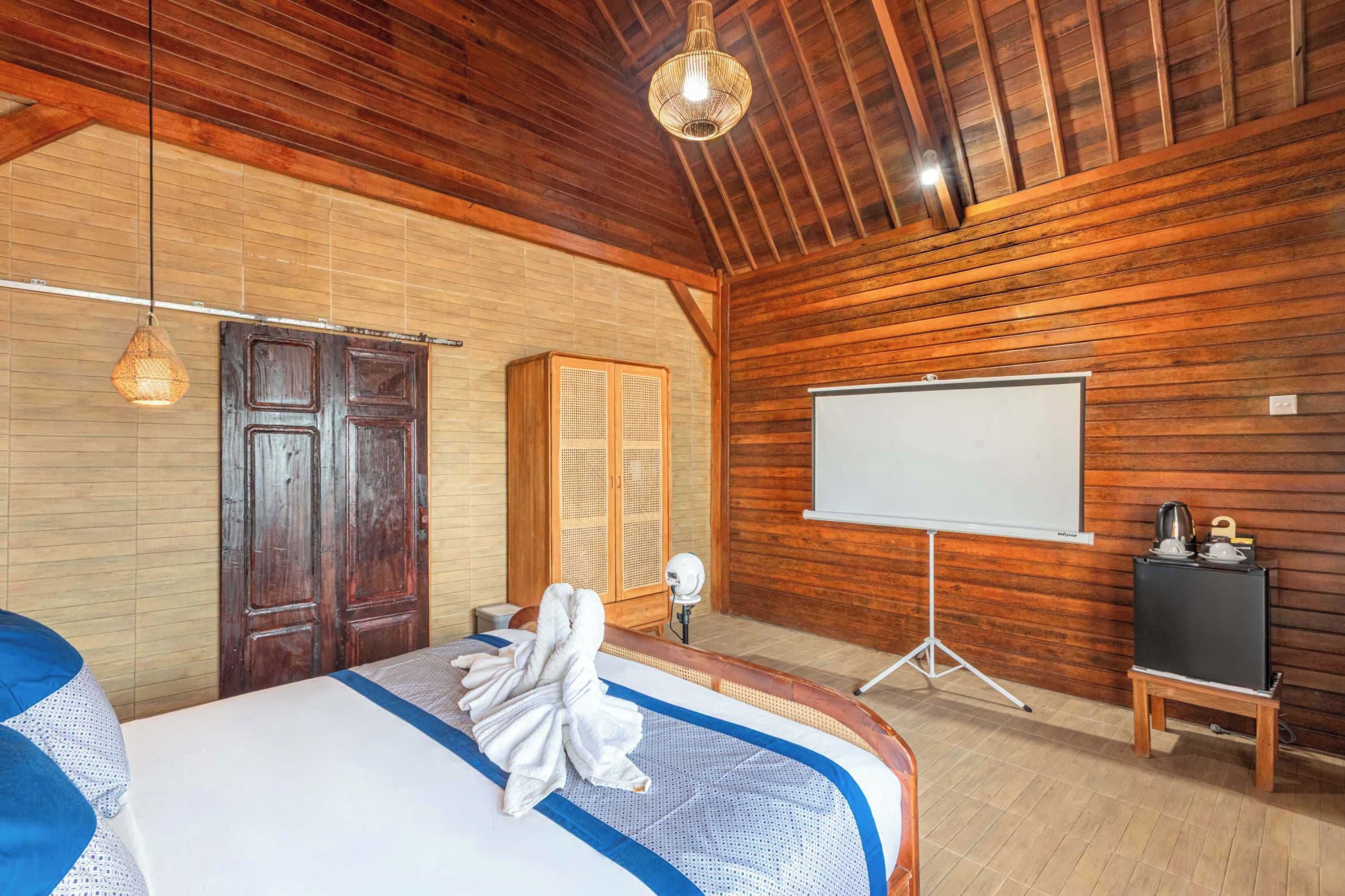 Ein Zimmer mit einem Bett, einer Wandtafel, einem Holzschrank und einer Pendelleuchte.