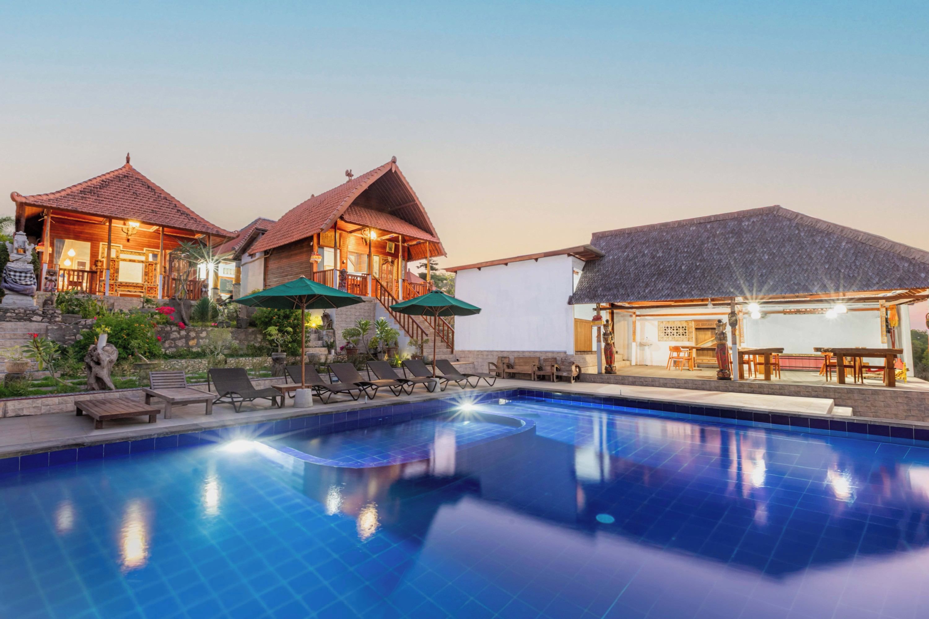 A resort with a swimming pool, lounge chairs, and a dining area.