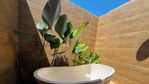 Un baño moderno con un lavamanos grande, redondo y color beige, y paredes de paneles de madera.