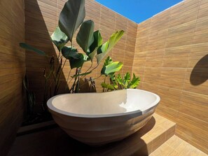 A modern bathroom with a large, round, beige sink and wooden panel walls. - Miyasabiasa Hills Nusa Penida (Klungkung)