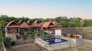 Un resort con varias construcciones tipo bungalow, una piscina y un jardín ajardinado.