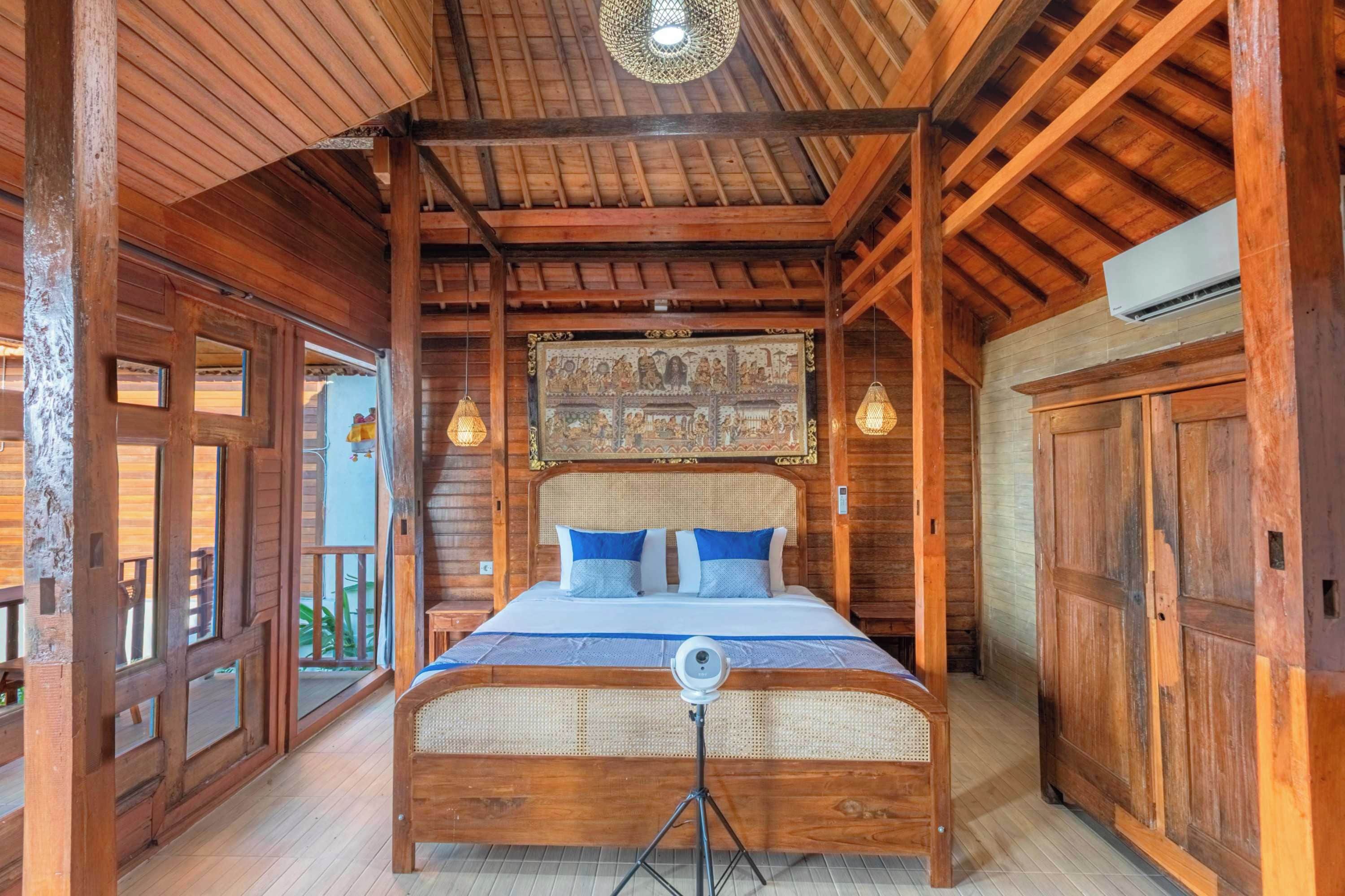 A wooden room with a bed, a ceiling light, and a wall-mounted picture.