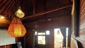 Un interior de madera con una cama, una lámpara colgante y vistas al exterior.