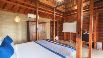 A wooden room with a bed, a wardrobe, a whiteboard, and a desk with a kettle.
