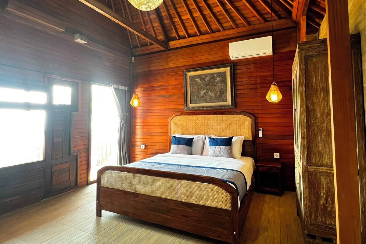 A wooden-paneled bedroom with a bed, a ceiling fan, and a framed picture on the wall.