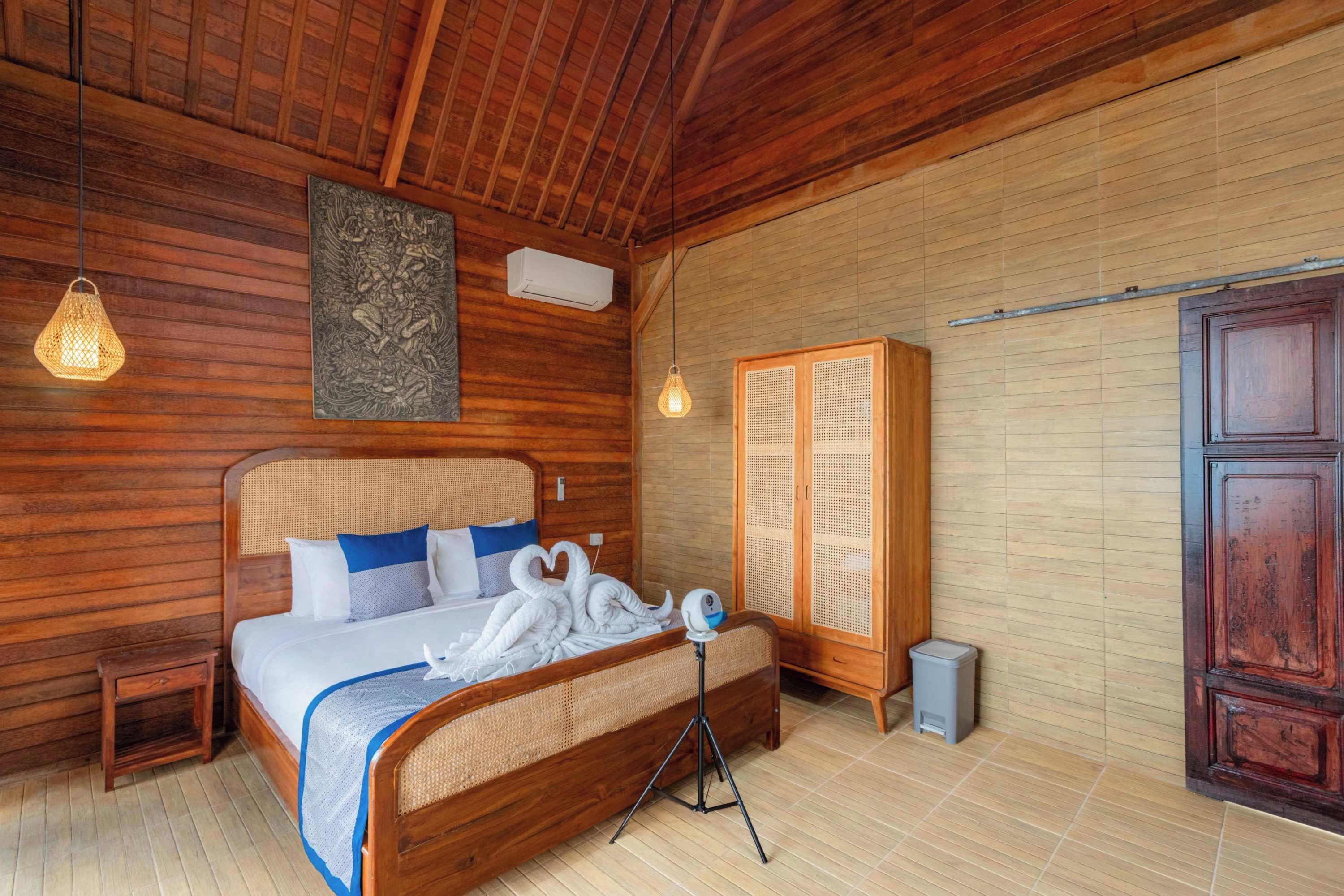Una habitación con paneles de madera, una cama, aire acondicionado de pared y un armario de ratán.