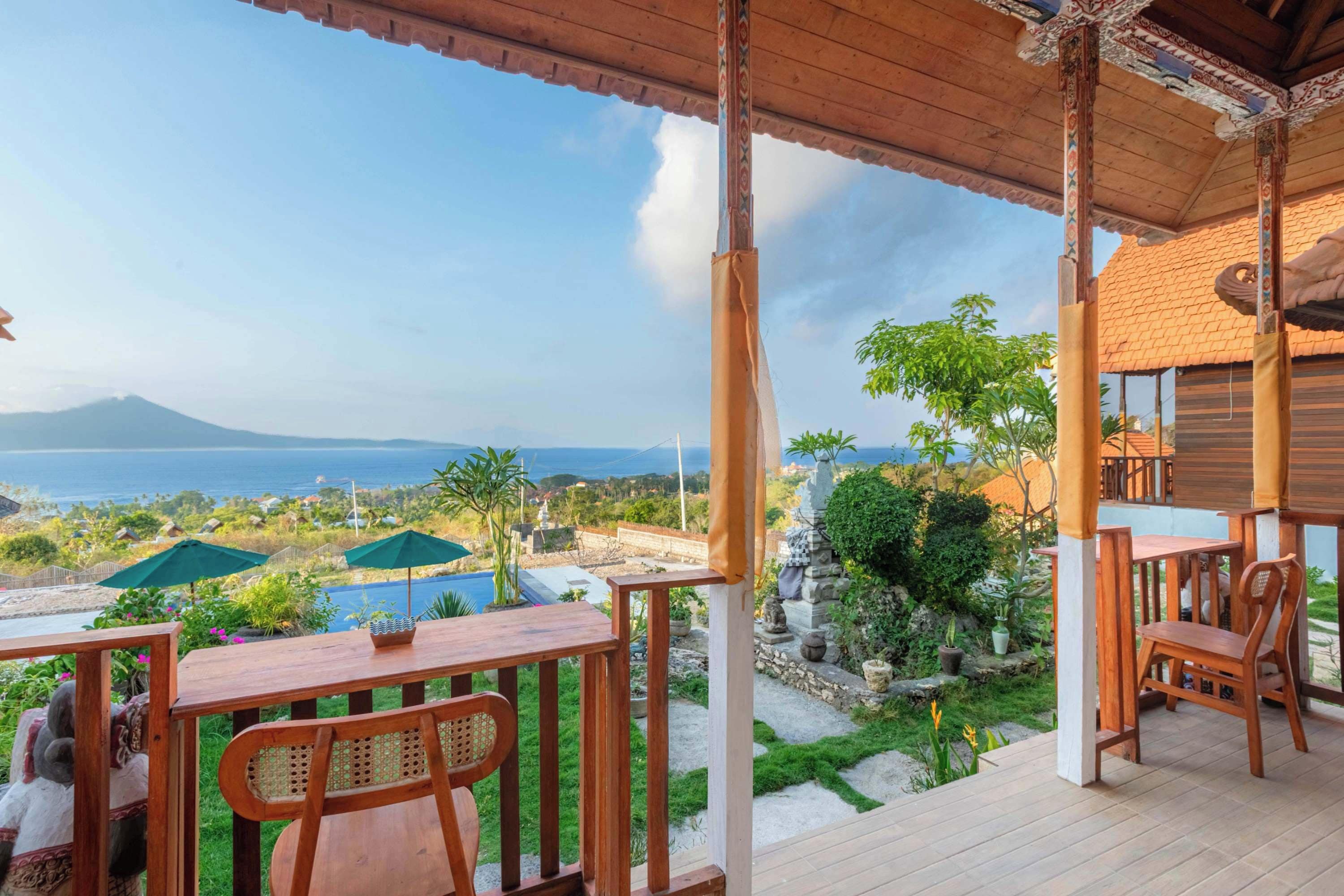 A wooden deck with a view of a swimming pool and a mountain in the distance.