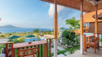 A wooden deck with a view of a swimming pool and a mountain in the distance.