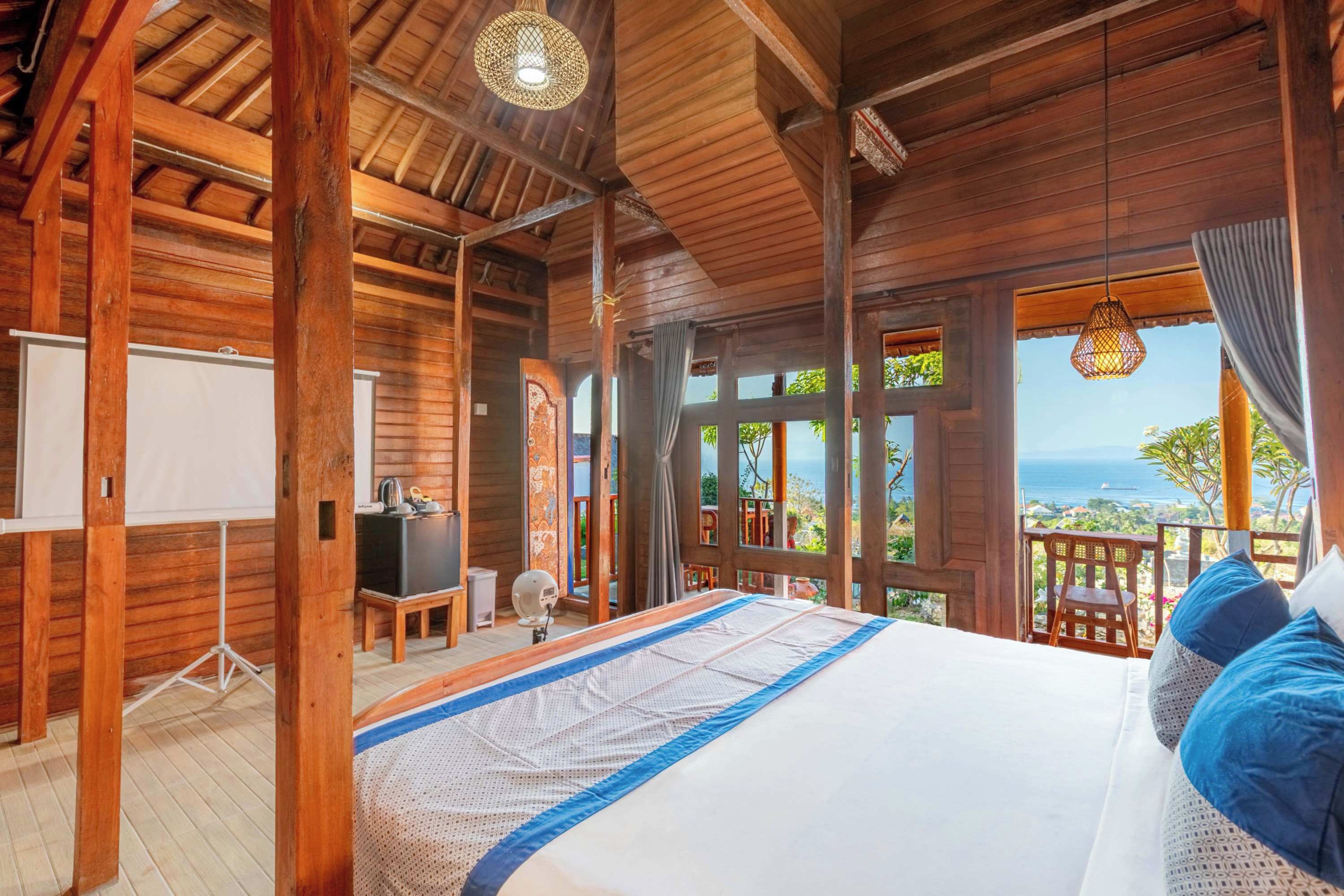 Una habitación de madera con una cama, un escritorio y vistas al océano.