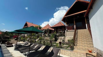 A resort with multiple bungalow-style buildings, outdoor seating, and a pool area.