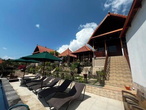 Un resort con varias construcciones tipo bungaló, mobiliario exterior y una zona de piscina.